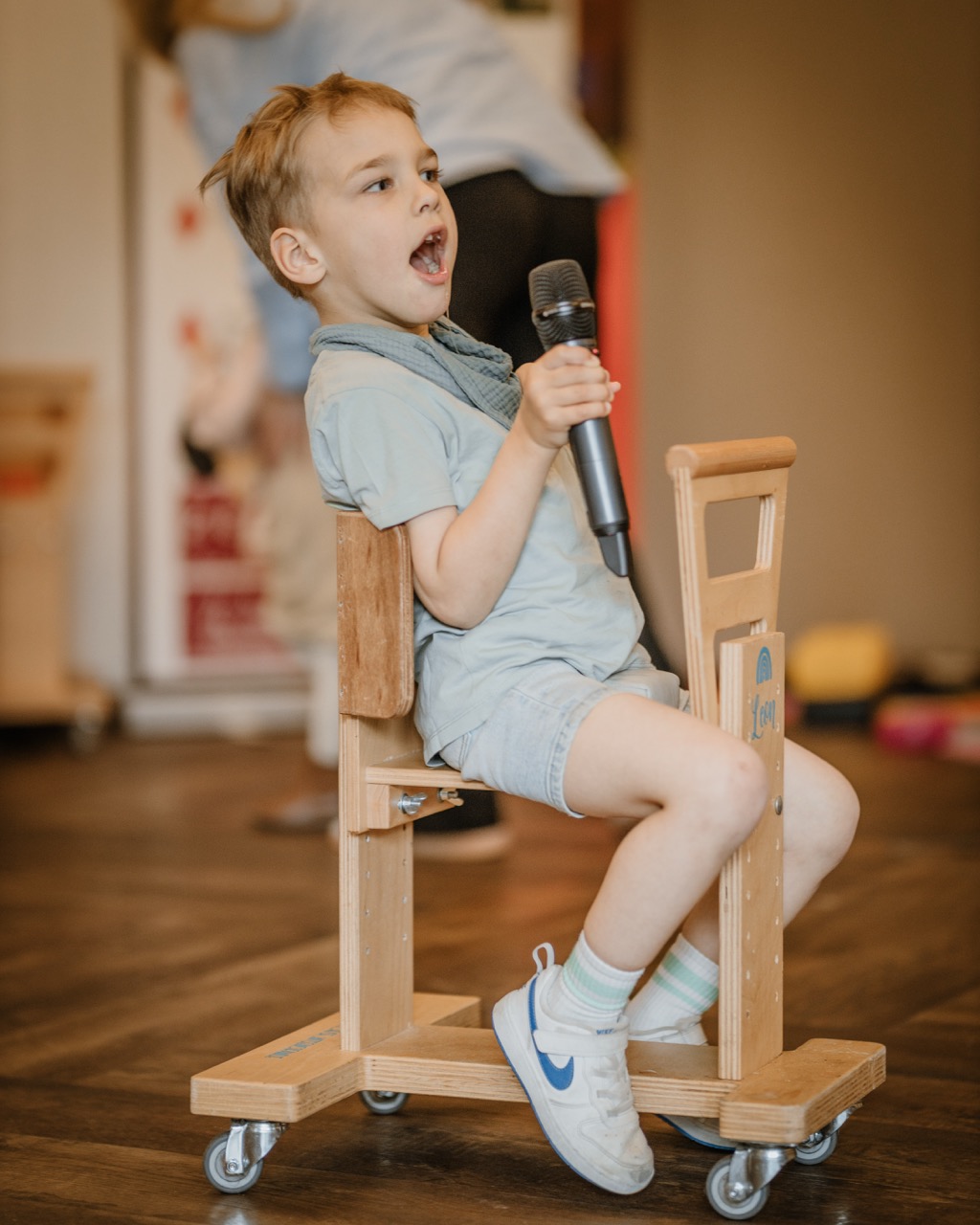 Leon auf seinem Holzwägelchen mit einem Mikro in der Hand