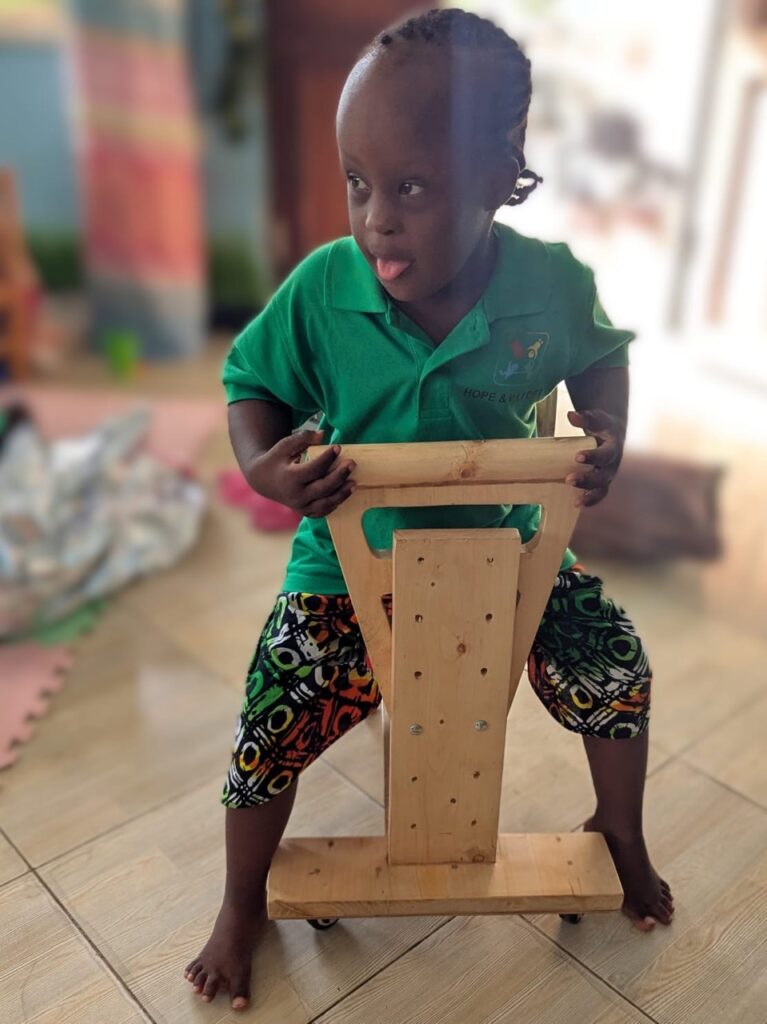 Kind aus Afrika sitzt auf dem Holzwägelchen